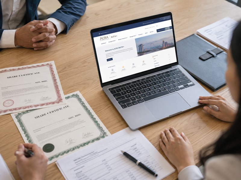 How to Issue New Shares in a Singapore Company: Allotment Process Explained A polished overhead shot of a meeting table with share certificates, a laptop showing ACRA BizFile+ on screen and a pen