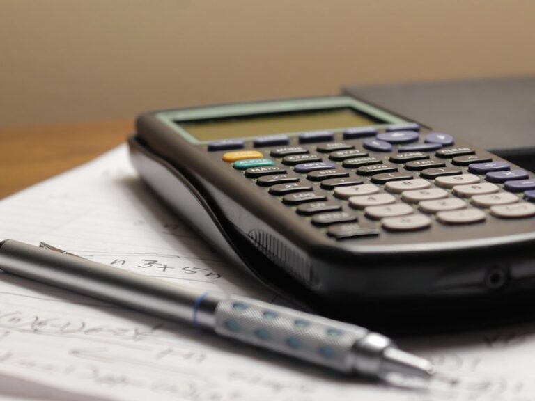 Calculator and pen beside financial paperwork