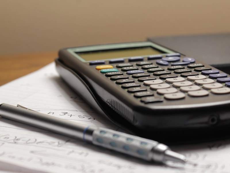 Calculator and pen beside financial paperwork