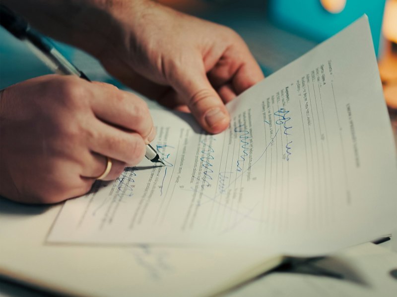 Man signing a document with a pen, representing a personal guarantee
