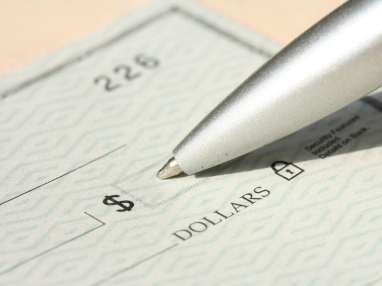 Close-up of a blank cheque with a pen resting near the amount line