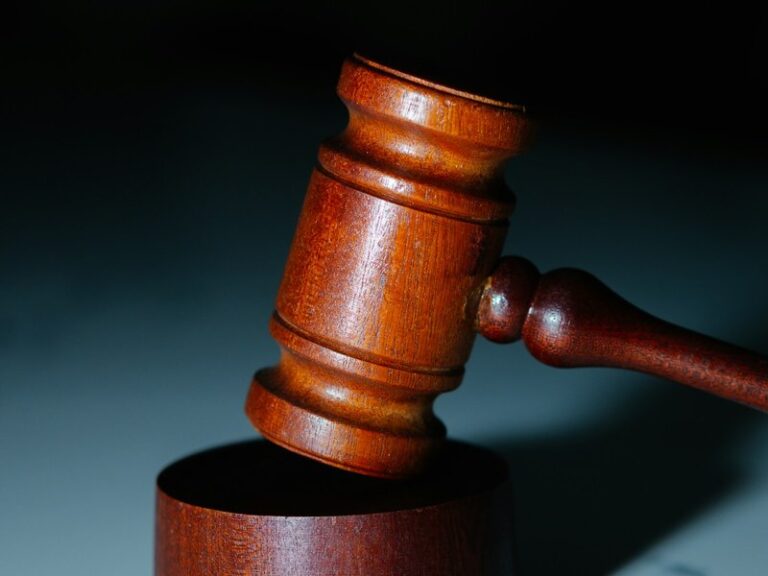 Wooden judge's gavel striking a sound block against a dark background, illustrating court fees and legal costs