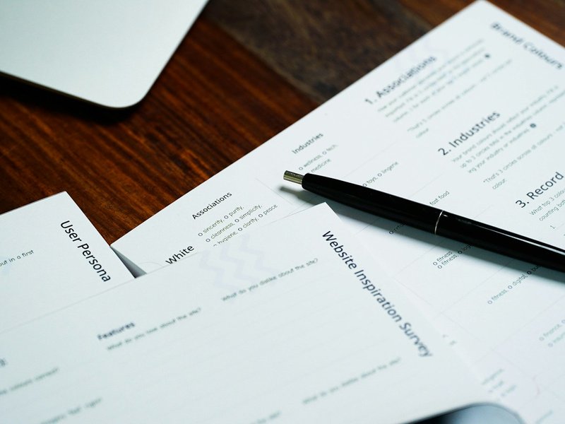 Printed documents and a black pen lying on a wooden desk