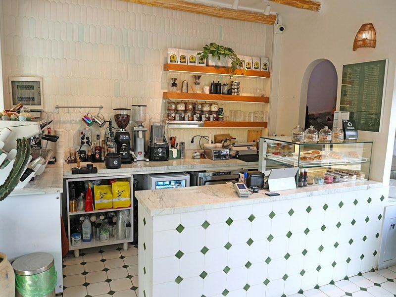Bright cafe counter with coffee machines, pastry display and tiled service counter, typical of a franchise food outlet