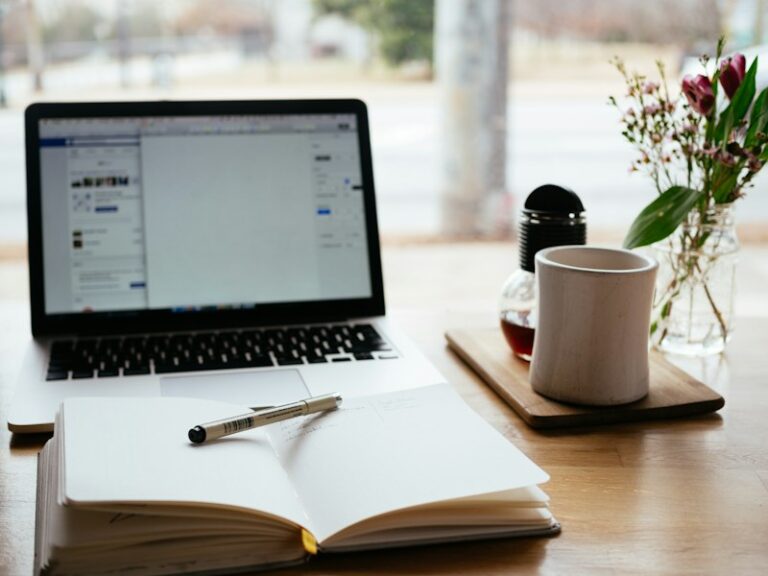 Laptop and open notebook with a pen on a wooden desk, ready for an ACRA annual return filing