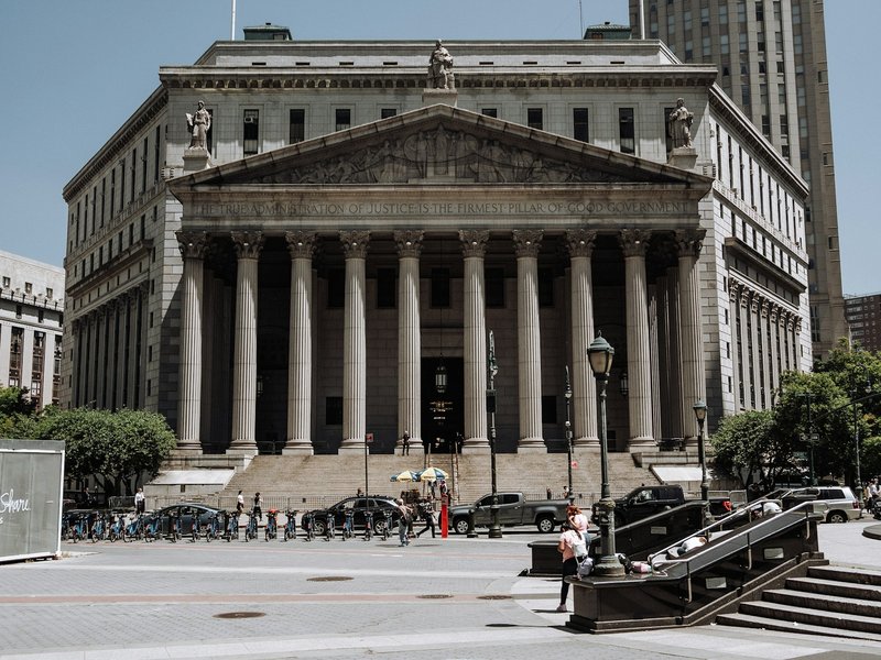 Neoclassical courthouse with a row of stone columns and wide front steps on a sunny day