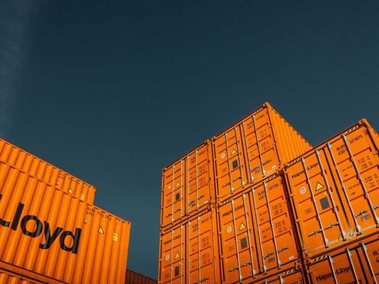 Stacked orange shipping containers against a dark blue sky
