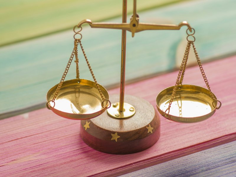 Small brass balance scale with two empty pans on a painted wooden surface