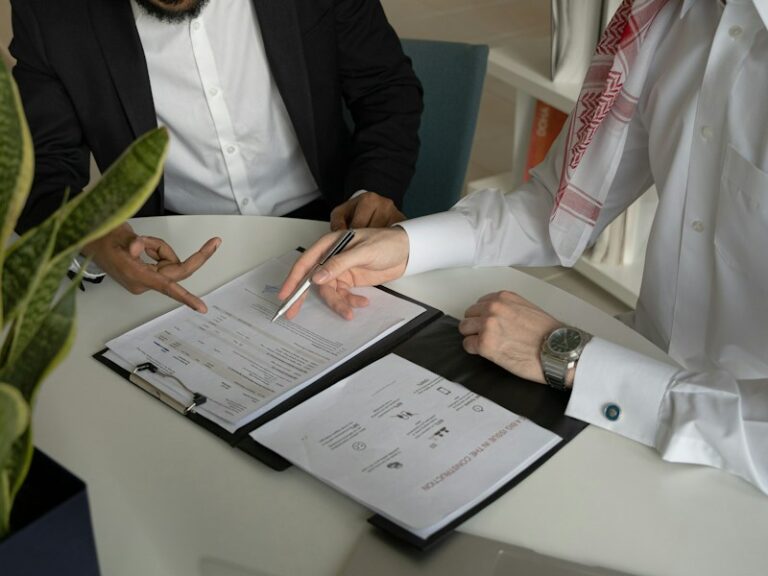 Two men sitting at a table reviewing papers with a pen, representing signing a nominee director agreement