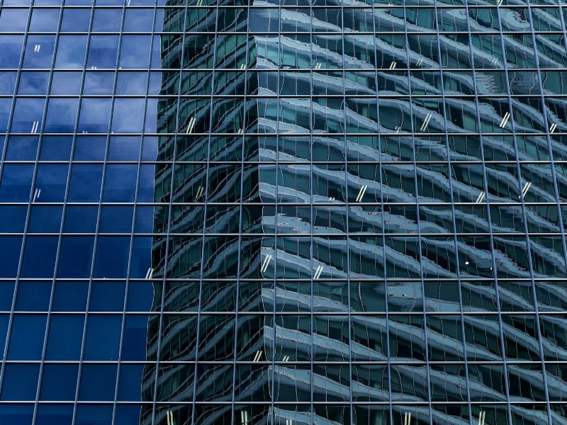 Office building in Raffles Place, Singapore, reflected against a blue sky