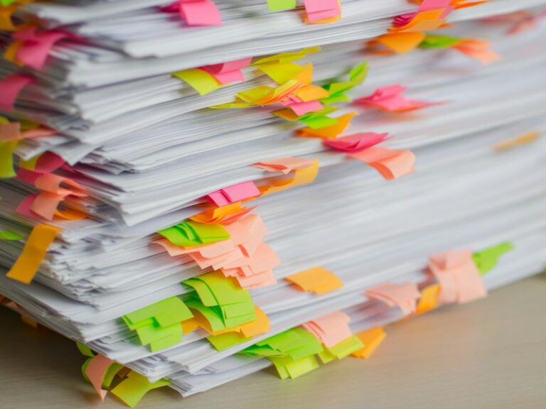 Stack of paper documents marked with colourful sticky tabs, representing records prepared for a PDPC investigation