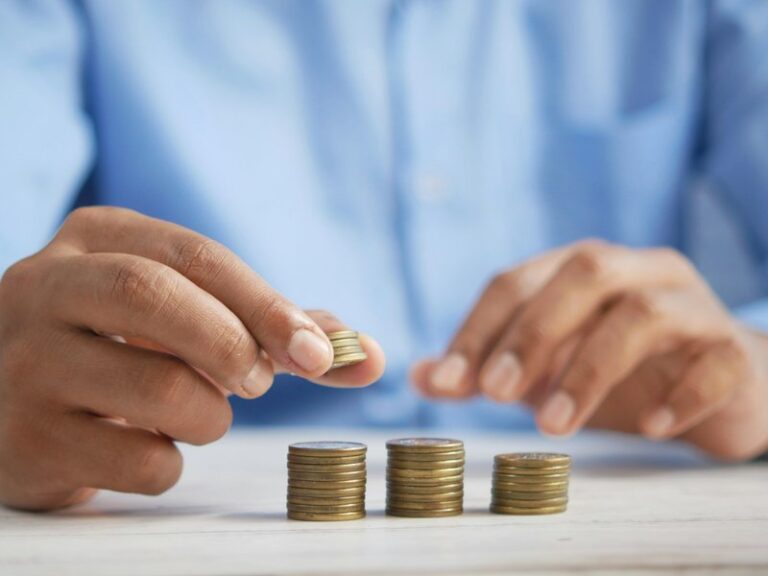 Person stacking coins into small piles on a white table, illustrating a petty cash float