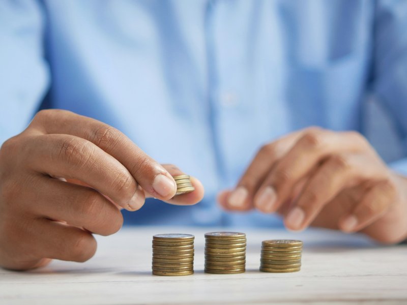 Person stacking coins into small piles on a white table, illustrating a petty cash float