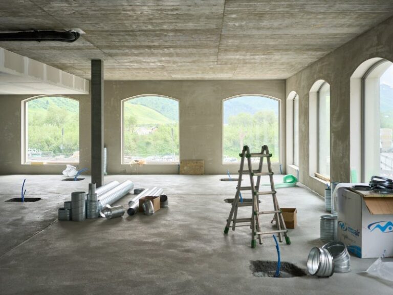 Commercial interior under renovation with a ladder and large windows