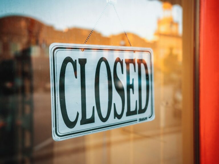 A 'Closed' sign hanging on a shop's glass door