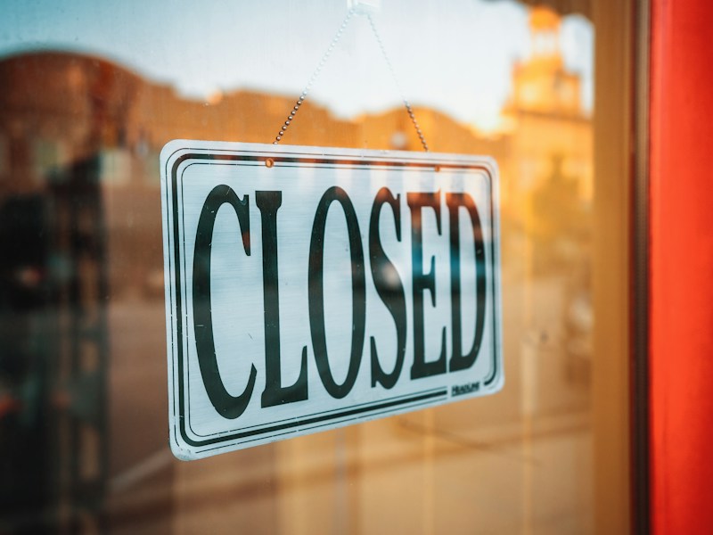 A 'Closed' sign hanging on a shop's glass door