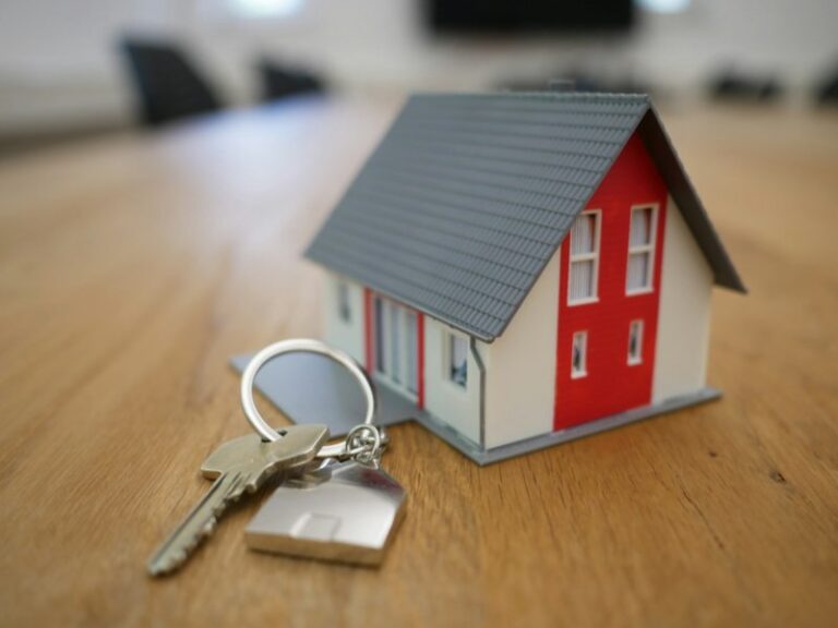Miniature white and red model house with keys on a wooden table