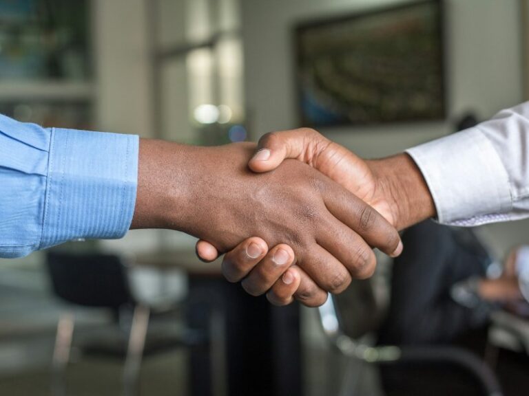 Two business people shaking hands across a table