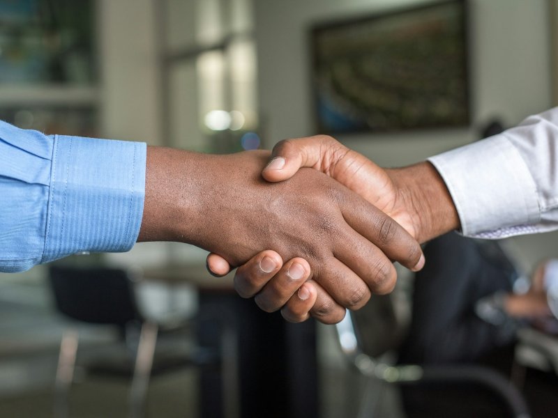 Two business people shaking hands across a table