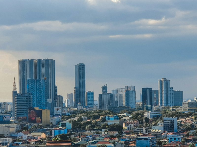 Quezon City skyline in Metro Manila, Philippines, with high-rise towers under grey clouds