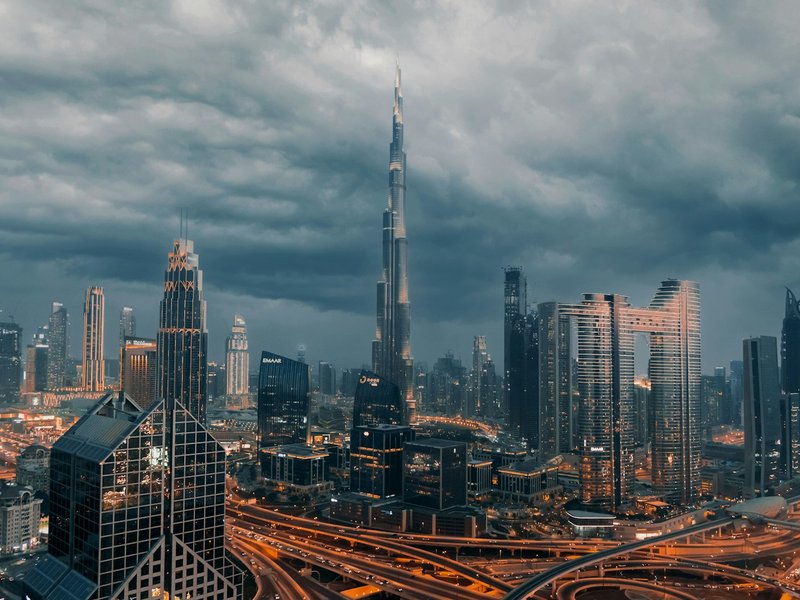 Burj Khalifa and the Downtown Dubai skyline under dark storm clouds at dusk