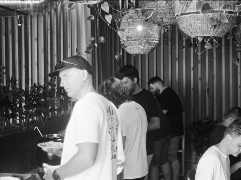 Colleagues helping themselves at a buffet during a casual company gathering, in black and white