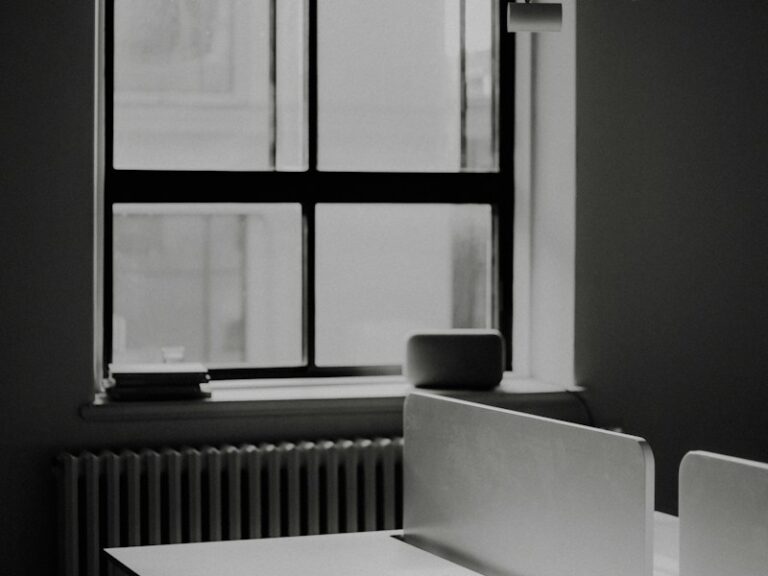 Empty office desk beside a window in black and white, suggesting a company that has ceased business