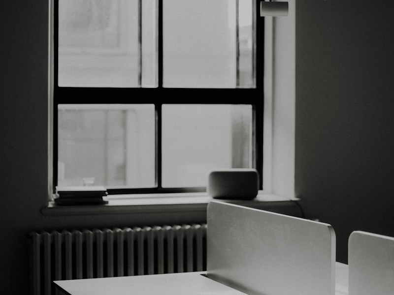 Empty office desk beside a window in black and white, suggesting a company that has ceased business