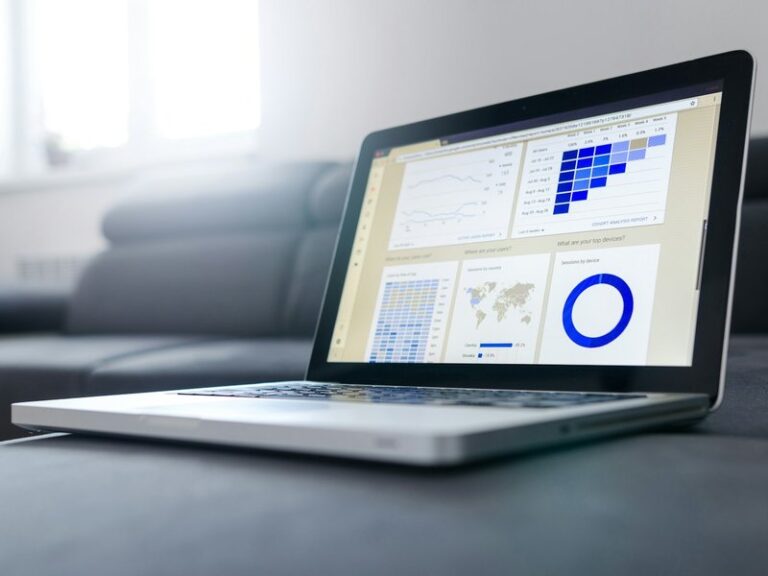 Laptop showing payroll and business charts on a desk, illustrating a payroll system handover